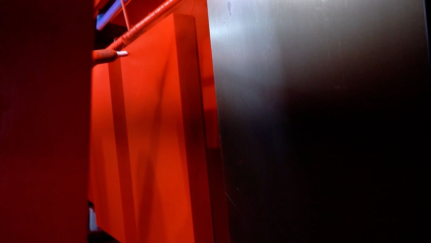 Industrial spray painting equipment applying a coating to a metal panel